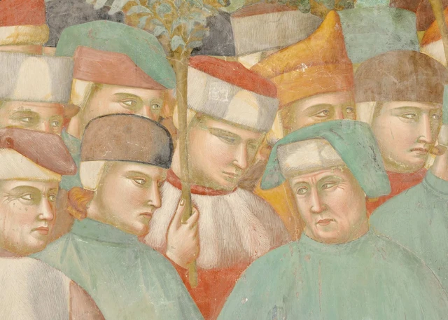 A closely gathered group of onlookers; a man in a brown cap raises his hand to his face.