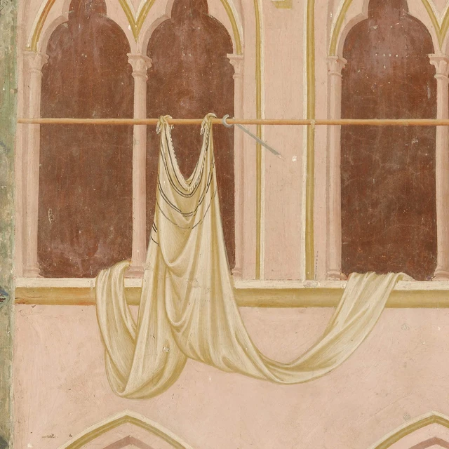 A pale cloth hangs from a pole in front of a building’s windows.