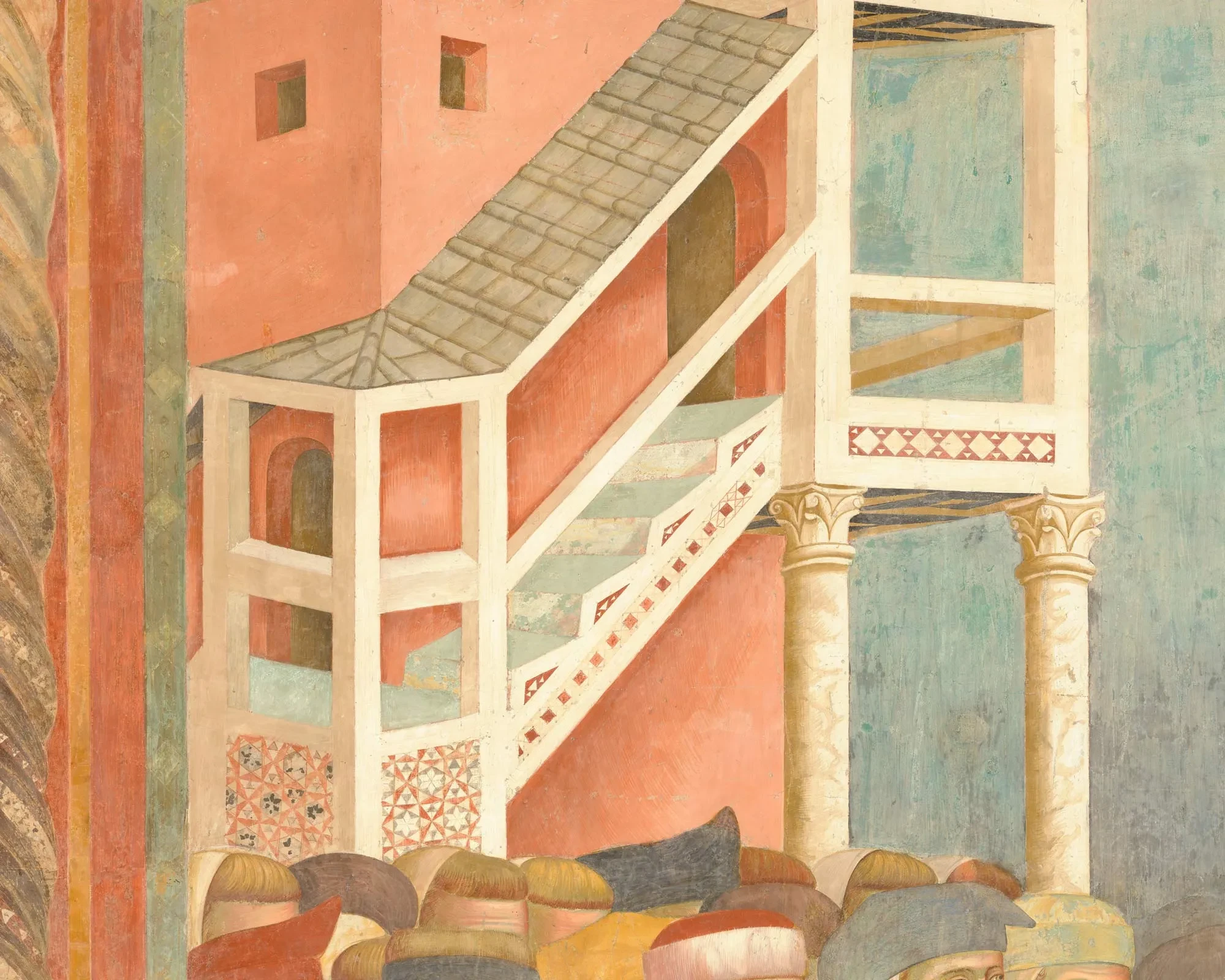 A covered external staircase with a decorated parapet in front of a red building.